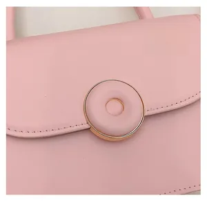 Detail of pink leather handbag showing smooth texture and golden circular metal buckle