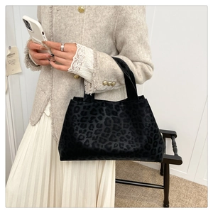 Detail of soft leopard print tote bag styled with a tweed jacket and white skirt