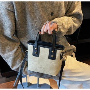 Détails des surpiqûres et rivets métalliques sur un sac seau en cuir bicolore beige