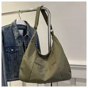 Détail du sac fourre-tout en nylon vert armée avec bandoulière large sur un cintre