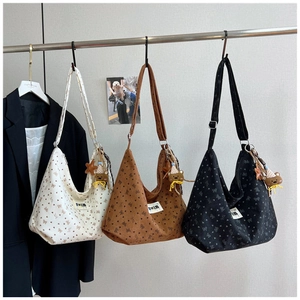 Detailed view of corduroy crescent bags in cream, brown and black with bear charms