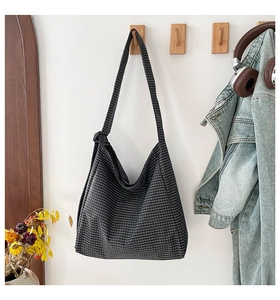 Detail of checkered tote bag fabric texture with wide strap hanging on wall hook