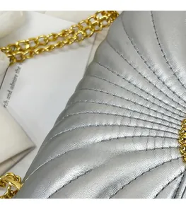 Close-up of fan-shaped quilted silver bag texture with golden hardware details