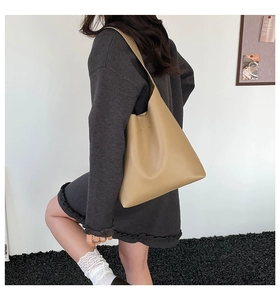 Detail of minimalist khaki leather hobo bag worn by a model in a casual outfit