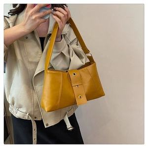 Close-up of bright yellow faux leather shoulder bag with gold metal eyelet strap detail