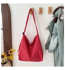 Detailed shot of red plaid canvas tote bag with adjustable strap on wall hook