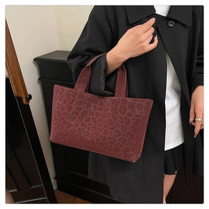 Side view of dark burgundy leopard print tote bag carried by a model in a minimal setting