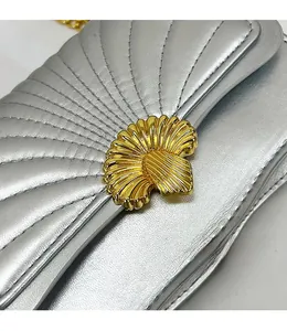 Macro shot of golden shell-shaped lock on silver quilted leather shoulder bag