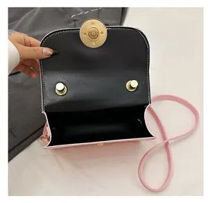 Detail showing the pink crossbody bag's single black interior compartment and gold lock