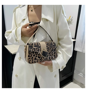 Close-up of leopard print shoulder bag with beige leather strap and gold geometric buckle