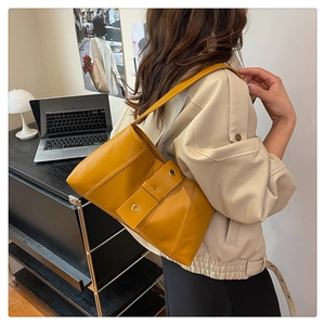 Detail of yellow PU leather shoulder bag with metallic eyelets in a lifestyle setting