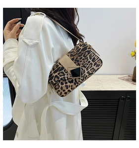 Detail view of stylish leopard print shoulder bag with gold clasp on white trench coat