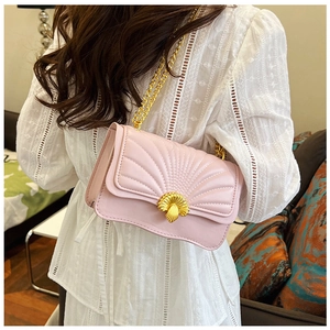 Close-up of quilted light pink shoulder bag featuring a gold shell clasp and metal chain