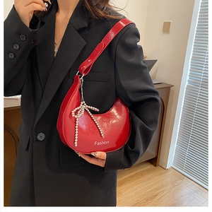Detail view of glossy red moon bag with silver pearl bow charm and Fashion print