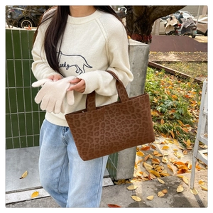 Detail of leopard print canvas tote bag held by a model with autumn street background