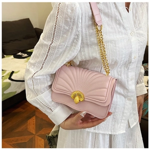 Detail of pink shell-shaped crossbody bag featuring fan quilting and gold metal clasp