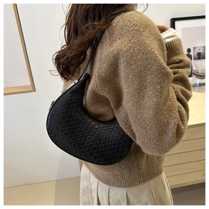 Detailed close-up of a black woven crescent bag worn as a shoulder bag on a model