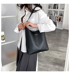 Minimalist black leather tote bag with yellow FASHION print worn by a fashion model