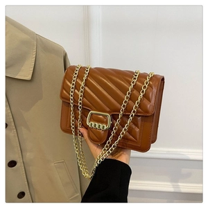 Close-up of brown quilted faux leather bag with V-pattern and gold rectangular buckle