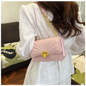 Detail of light pink shell-quilted crossbody bag with golden shell-shaped metal clasp