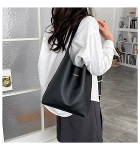 Close-up of black matte faux leather tote bag with gold FASHION text detail