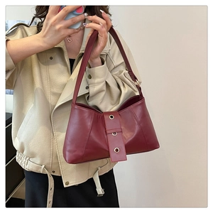 Detail of burgundy leather underarm bag with vintage rivet straps for daily wear