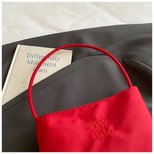 Detail of red nylon handbag featuring Hope and future embroidery and tubular handle