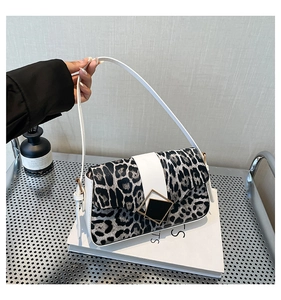 Close-up of leopard print shoulder bag with white leather strap and metallic buckle