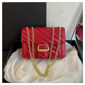 Close-up of red quilted crossbody bag with V-shaped stitching and gold chain strap