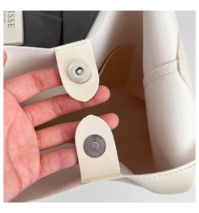 Close-up of beige leather tote interior with magnetic metal clasp and fabric lining