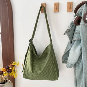 Green checkered canvas tote bag with adjustable strap in a minimalist lifestyle setting
