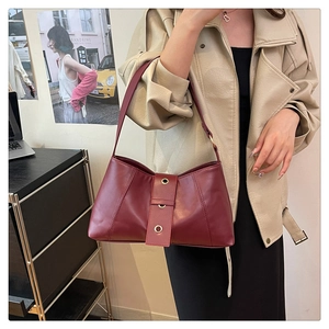 Close-up of burgundy leather underarm bag featuring three gold grommet eyelets detail