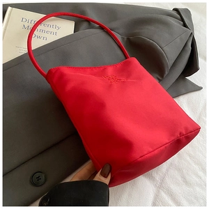 Detail of red nylon tote bag with embroidery on casual gray blazer background