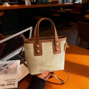 Sac seau en toile rétro avec poignées en cuir contrastées sur un bureau en bois
