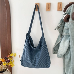 Minimalist navy blue plaid tote bag hanging on wall with a clean aesthetic indoor scene