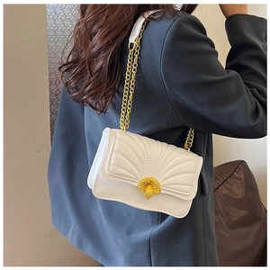 Detail of white quilted crossbody bag featuring a golden shell-shaped metal clasp