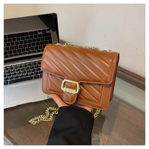 Close-up of brown quilted leather bag featuring gold metal buckle and chain strap detail