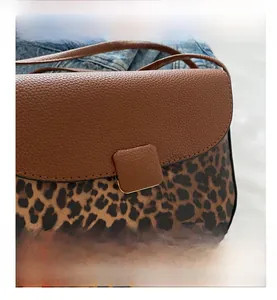 Detail view of leopard print saddle bag with brown lychee leather and gold buckle