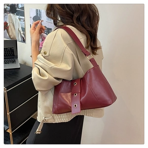 Detail of vintage burgundy hobo bag showing rivets and adjustable strap in use