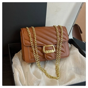 Detail of brown chevron quilted bag with gold chain and clasp in a gift box