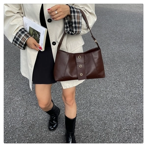 Close-up of retro brown shoulder bag featuring metallic gold rings and soft leather texture