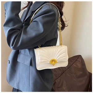 Detail of white crossbody bag with gold shell clasp and stylish quilted fan pattern