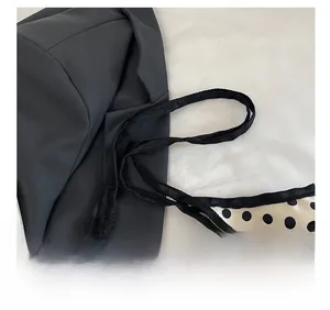 Close-up of comfortable black thin shoulder strap on polka dot canvas tote bag