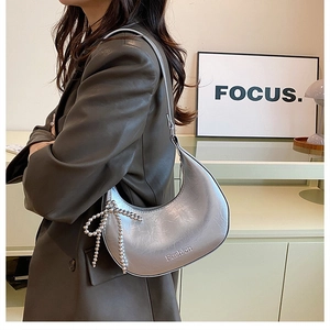 Detail of silver metallic hobo bag featuring bead bow charm and Fashion lettering print