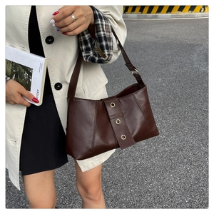 Close-up of retro dark brown baguette bag featuring three metallic gold-tone eyelets
