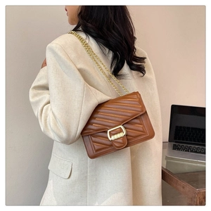 Detail of a brown quilted leather chain bag with a gold buckle for office style
