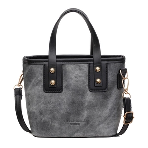 Bolso tipo cubo en denim gris y cuero negro con herrajes dorados y correa ajustable