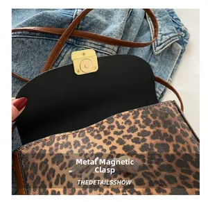 Macro shot of the gold magnetic clasp on a leopard print saddle bag with brown strap