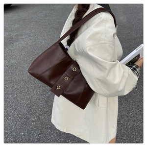 Detail view of deep brown leather bag featuring three gold rivet buckles and metallic hardware