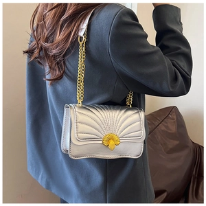 Detail of silver shell pattern shoulder bag with gold shell buckle on grey blazer